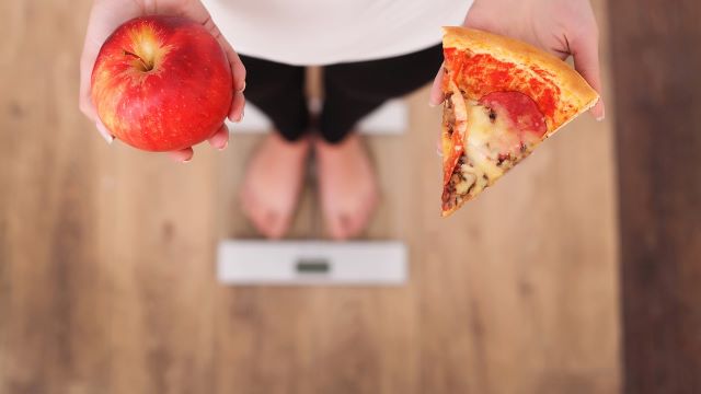 食べ物をもって体重計に乗る女性