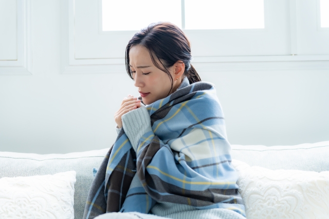 寒そうにソファに座る女性